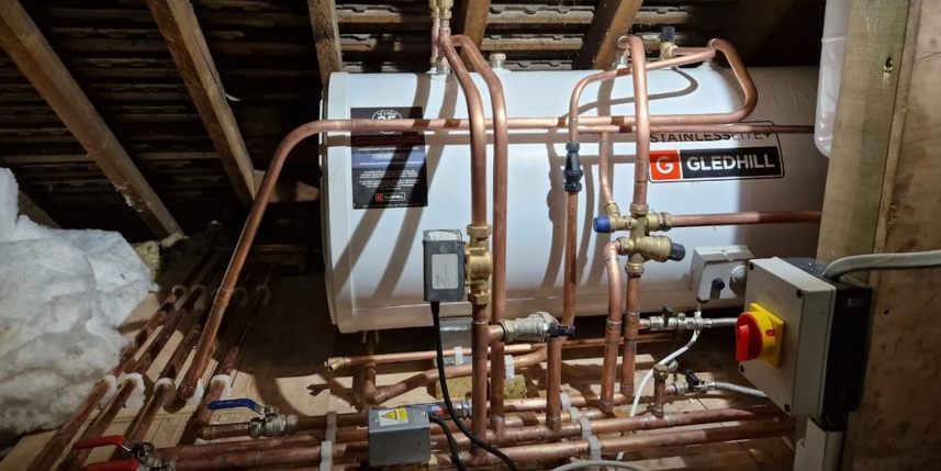 Gledhill StainlessLite unvented hot water cylinder with structured copper pipework, brass valves and isolation switch installed in a loft, central heating installation, London.