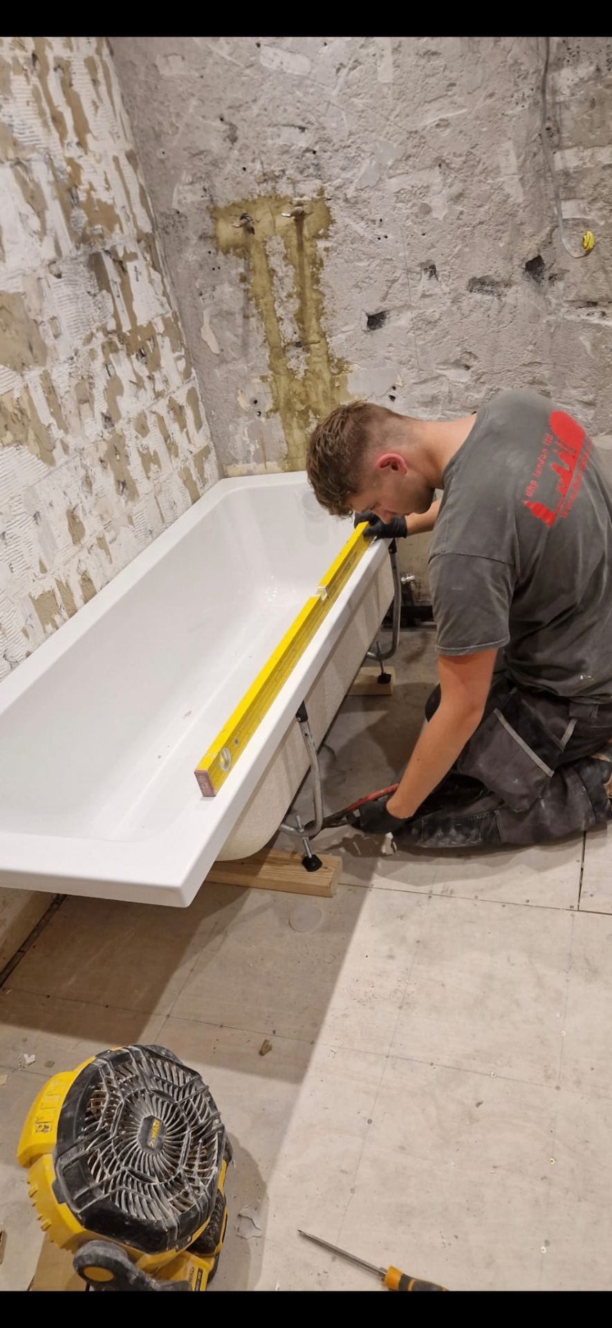 DHP London engineer levelling a new bath during a bathroom installation
